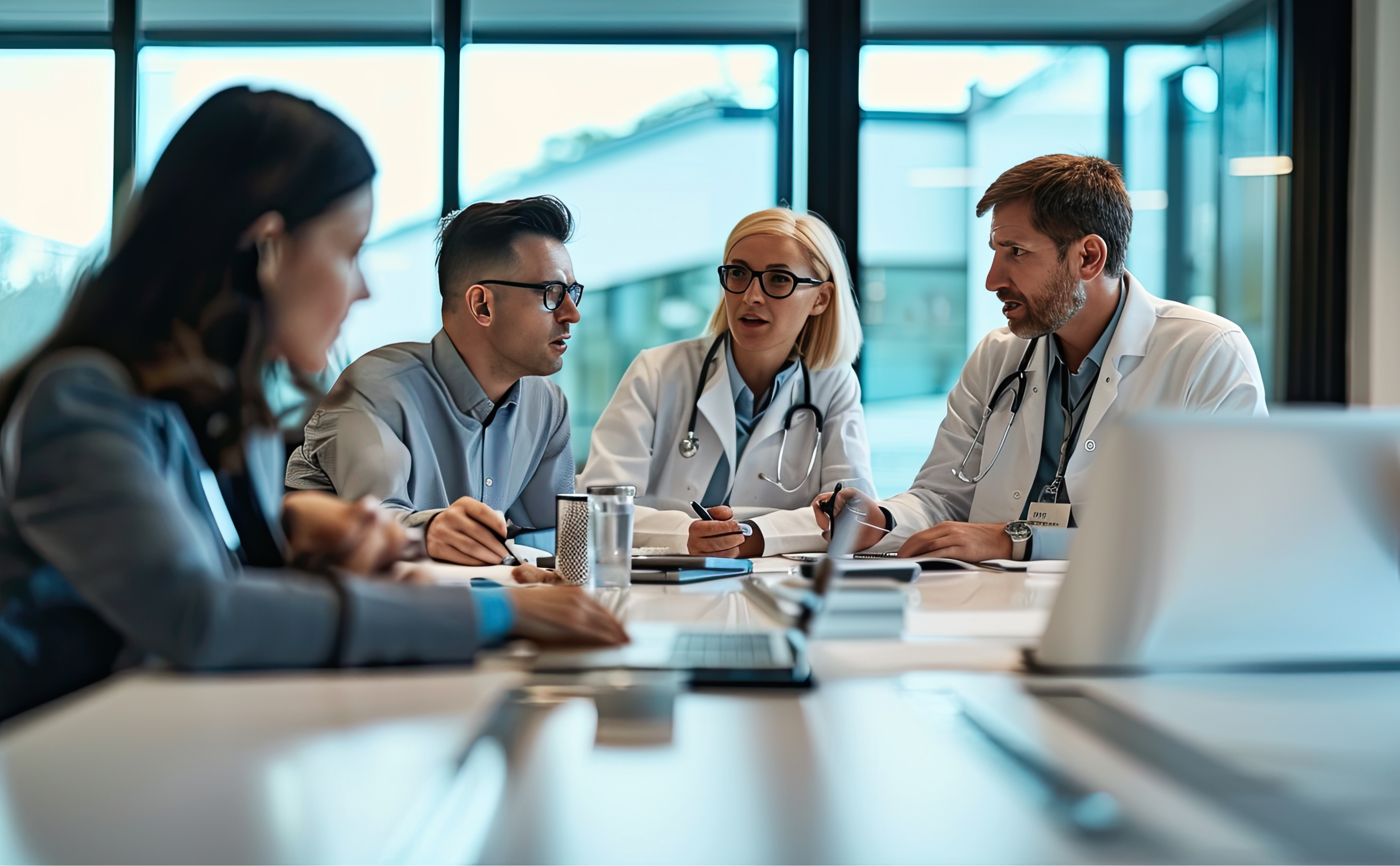A photo showing a group of medical professionals talking together while sitting at a table.