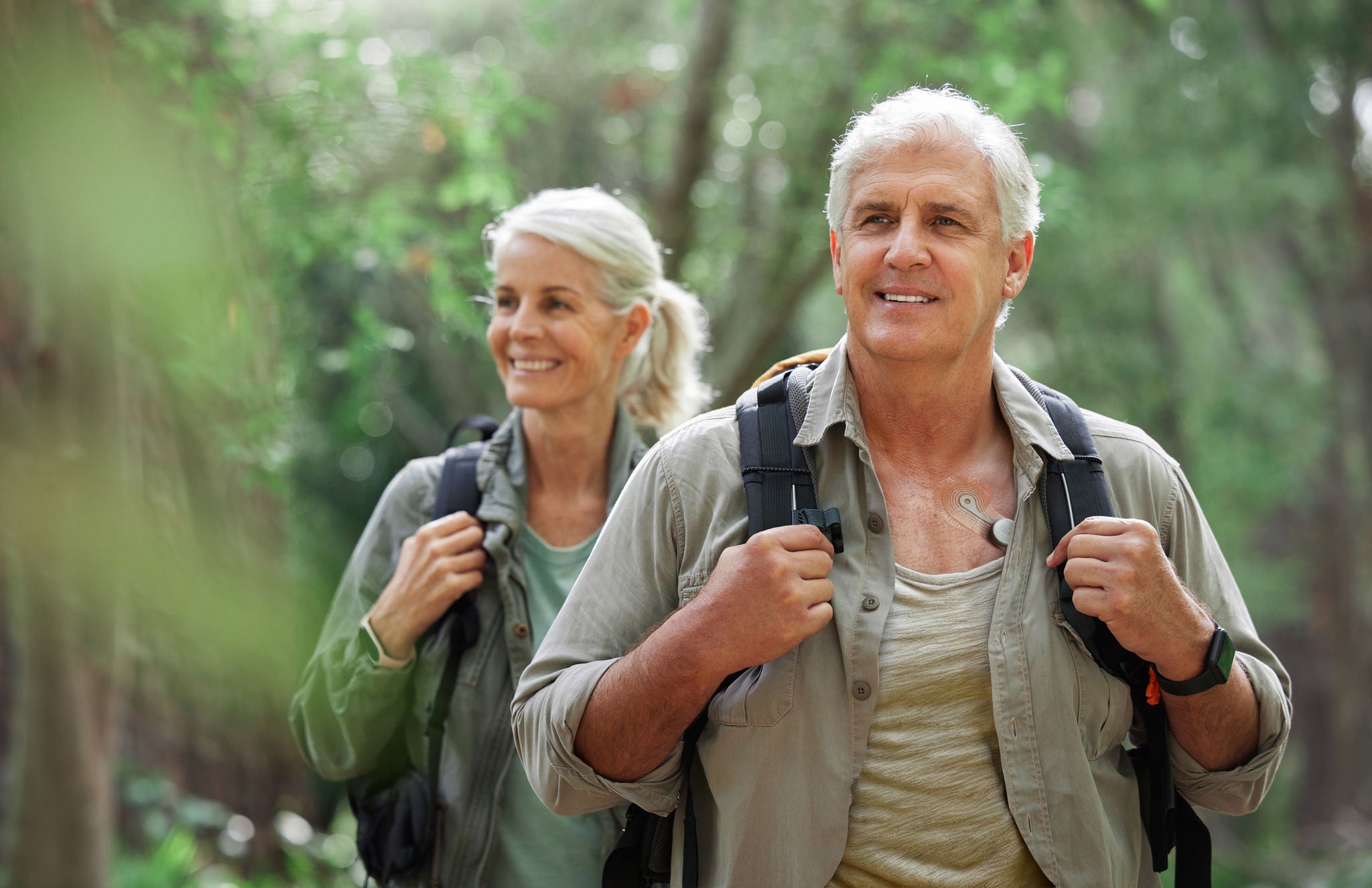 Hiking, elderly couple and active seniors in a forest, happy and relax while walking in nature. Senior, backpacker and woman with man outdoors for travel, freedom and healthy lifestyle in retirement.